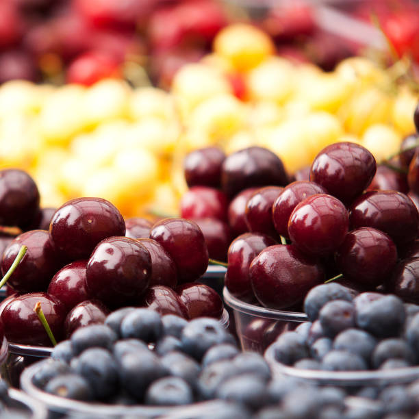 reife kirschen und heidelbeeren werden in plastikbecher gelegt - claret cup stock-fotos und bilder