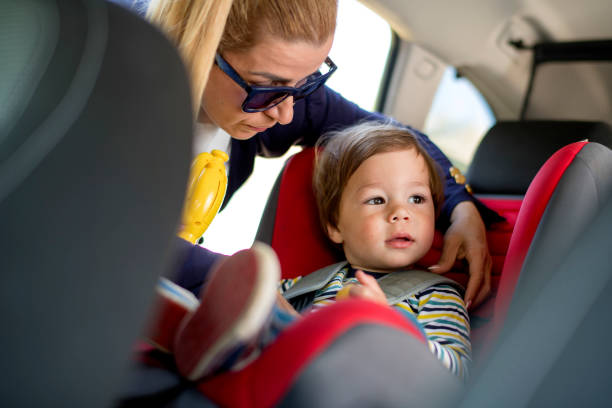istock Mom strap adorable son into car seat 1147964992