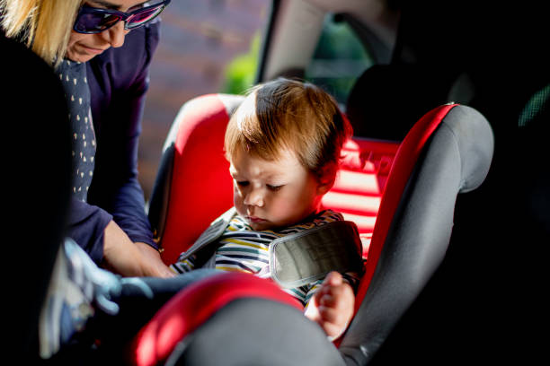 istock Mom strap adorable son into car seat 1147965497