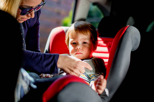 istock Mom strap adorable son into car seat 1147965540