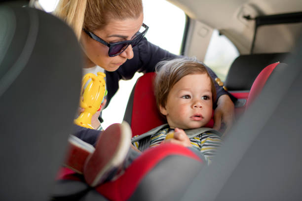 istock Mom strap adorable son into car seat 1147966300