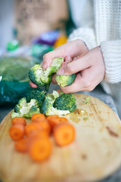 istock Female hands preparing raw broccoli on wooden board 1147967957