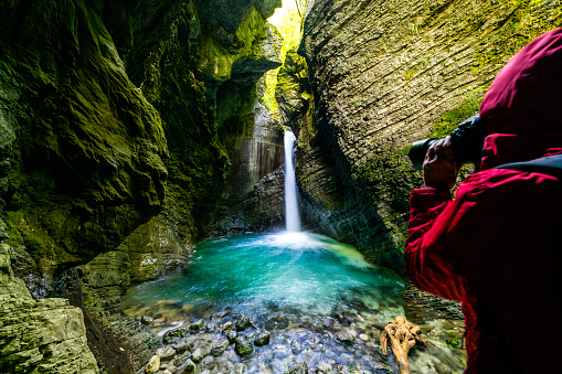 Photographer Exploring the Amazing Kozjak waterfall in Julian Alps canyon in Slovenia, Europe.