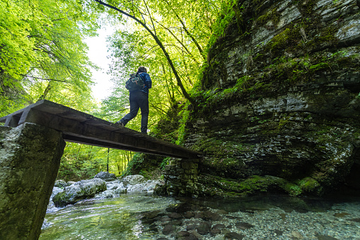 Old wooden suspension bridge in canyon of the river Nera in the National park Nera-Beusnica. Small group of unrecognizable persons on the end of the bridge.