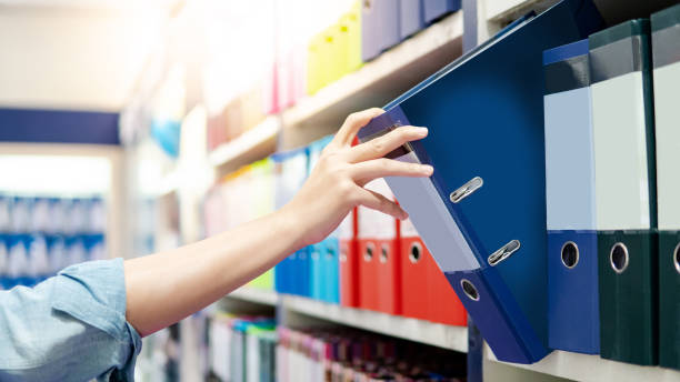 istock Male hand choosing new blue ring binder file folder from colourful shelf display in stationery shop. Buying office supplies concept 1147969731