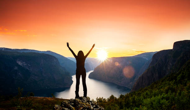 silhouette einer frau bei sonnenuntergang am fjord - mountain peak norway reflection sunlight stock-fotos und bilder