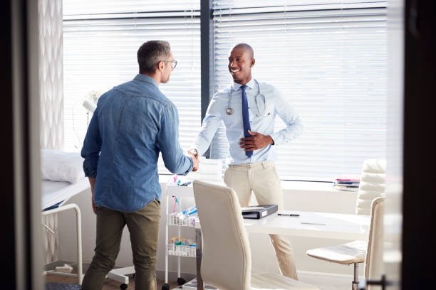 paziente maschio maturo che stringe la mano al medico in carica - mature adult men male african descent foto e immagini stock