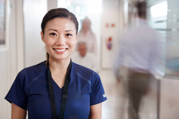 にぎやかな病院の廊下でスクラブを着た笑顔の女性看護婦の肖像 - chinese doctor ストックフォトと画像