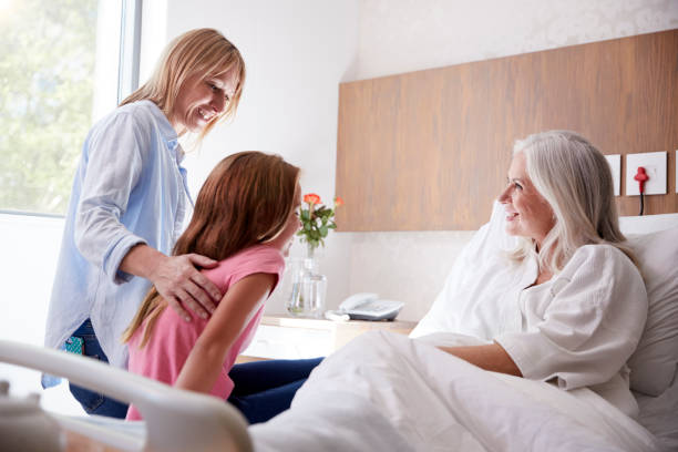 家族病院訪問で祖母と話をしている孫娘 - adult caucasian senior adult family ストックフォトと画像