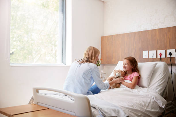 Mother Visiting Daughter Lying In Bed In Hospital Ward Mother Visiting Daughter Lying In Bed In Hospital Ward sick child hospital bed stock pictures, royalty-free photos & images