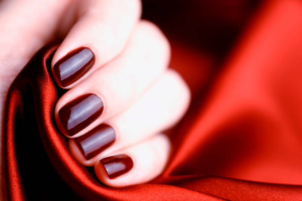 istock Manicure with burgundy nails on burgundy background 1147976787