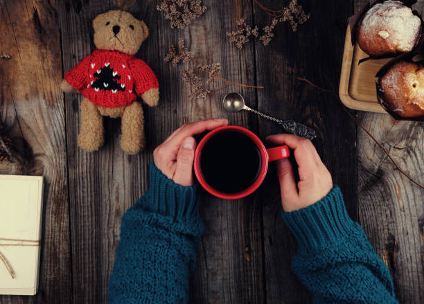 istock women's hands in a green knitted sweater holding a red ceramic mug with black coffee 1147976943