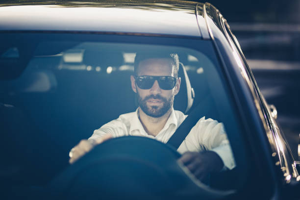 istock Young businessman with sunglasses driving a car to work. 1147978139