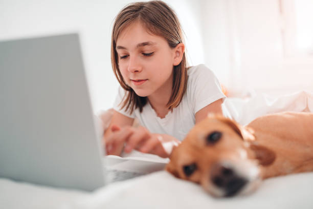 istock Girl lying on the bed with dog and using laptop 1147978351