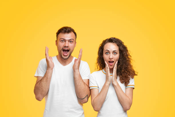 istock Amazed couple looking at camera on orange background 1147978479