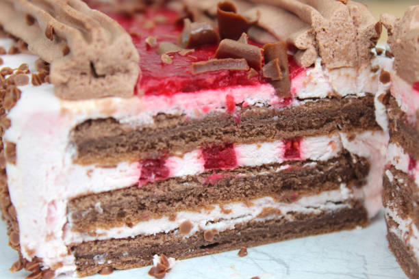 istock Image of homemade rectangular shaped chocolate cake with layers of sponge cake, fresh whipped cream, raspberry jam / raspberry coulis, cocoa and chocolate butter icing cream, chilled and ready to eat as an indulgent pudding desert after dinner party meal 1147979654