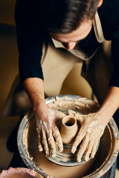 istock Man potter working on potters wheel making ceramic pot from clay in pottery workshop 1147982228