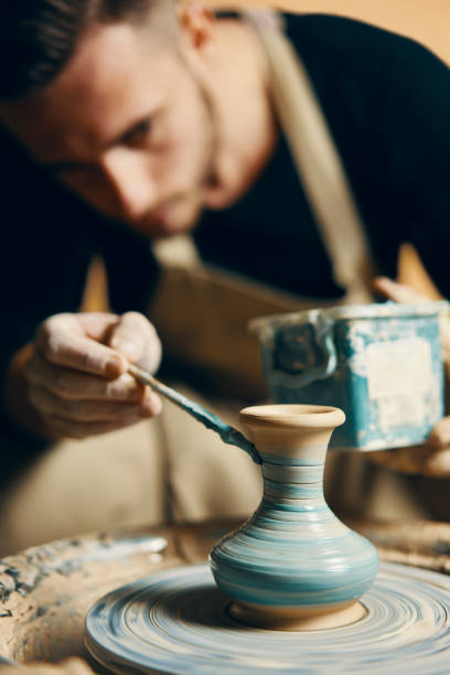 istock Man painting handmade pottery at ceramic workshop 1147982265