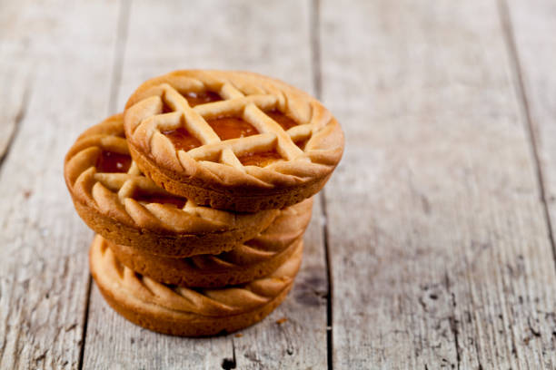 crostate fresche al forno con marmellata o marmellata di albicocche che si riempiono su uno sfondo rustico del tavolo in legno - marmalade baked biscuit brown foto e immagini stock