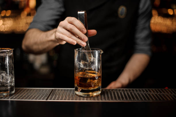 istock Bartender adding ice in glass with ice tongs 1147993547