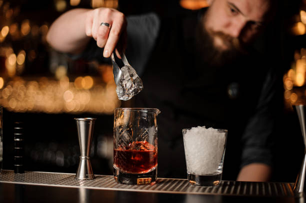 istock Bartender adds ice in glass with special ice tongs 1147993624