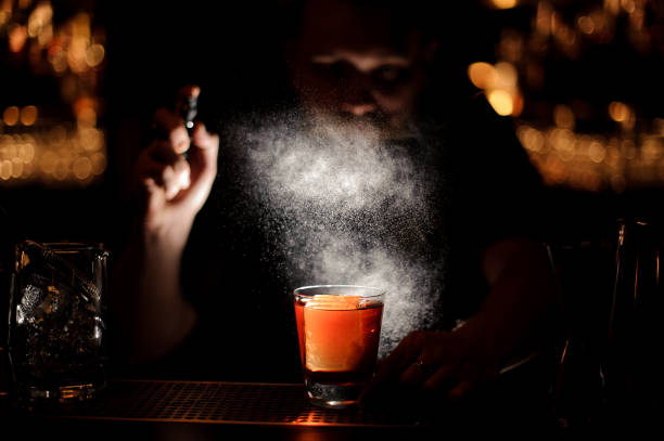 istock Darkened close shot of bartender pouring cocktail using sprayer 1147997443