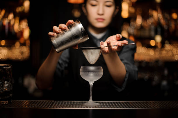 istock Female bartender prepares alcohol cocktail with shaker and sieve 1147997797