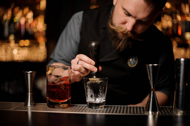istock Male bartender adds ice in glass with ice picker 1147998103