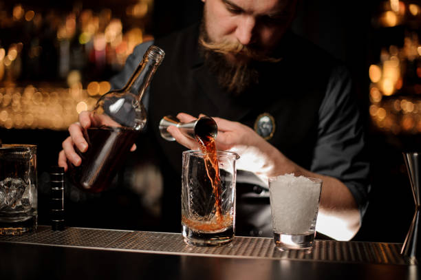 istock Male bartender pouring an alcohol cocktail with jigger 1147998783