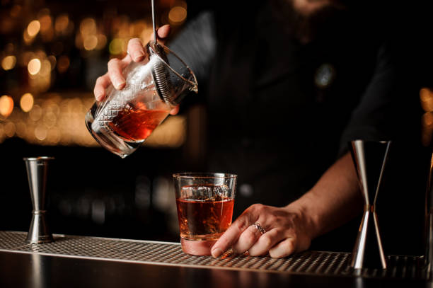 istock Male bartender pours alcohol cocktail with strainer 1147998810