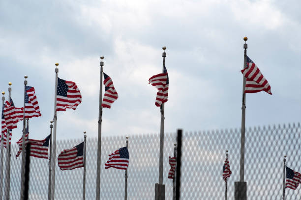 istock Waving usa flags behind fence grid 1147999120