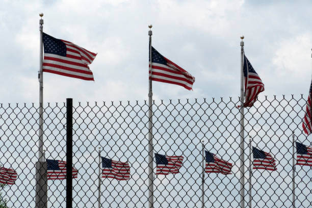 istock Waving usa flags behind fence grid 1147999141