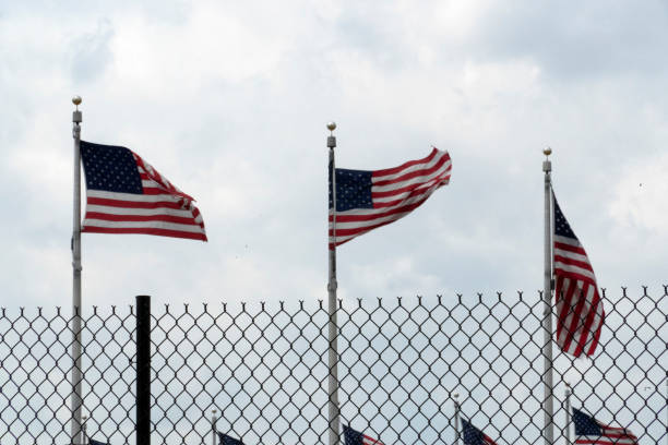 istock Waving usa flags behind fence grid 1147999145