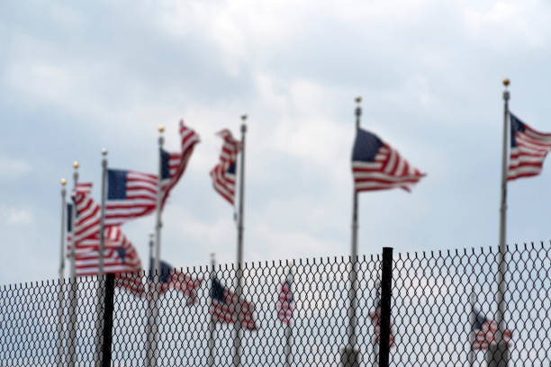 istock Waving usa flags behind fence grid 1147999180