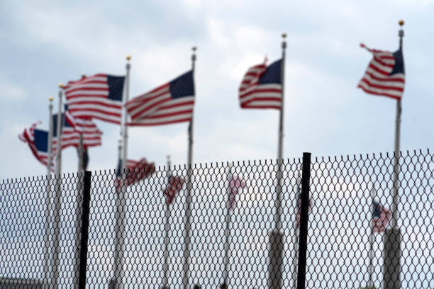 istock Waving usa flags behind fence grid 1147999208