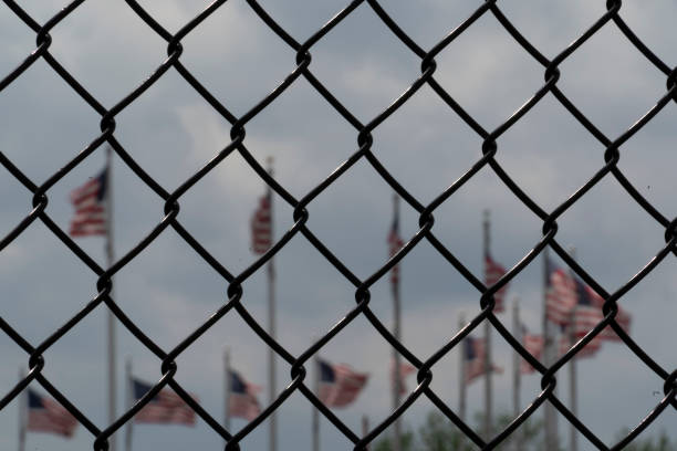 istock Waving usa flags behind fence grid 1147999216