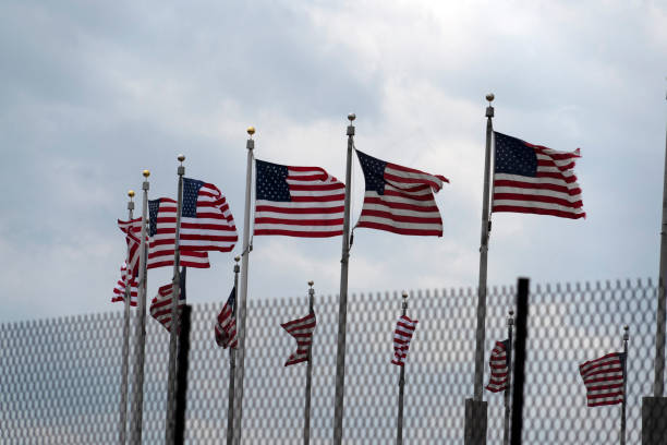 istock Waving usa flags behind fence grid 1147999232