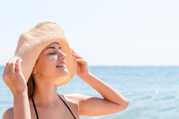istock Smiling woman in hat is applying sunscreen on her face. Indian style 1148000623