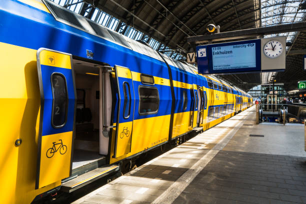 train hollandais jaune sur la plate-forme de la gare d’amsterdam centraal le matin. centraal est la plus grande gare ferroviaire d’amsterdam, aux pays-bas et un grand hub ferroviaire national - culture néerlandaise photos et images de collection