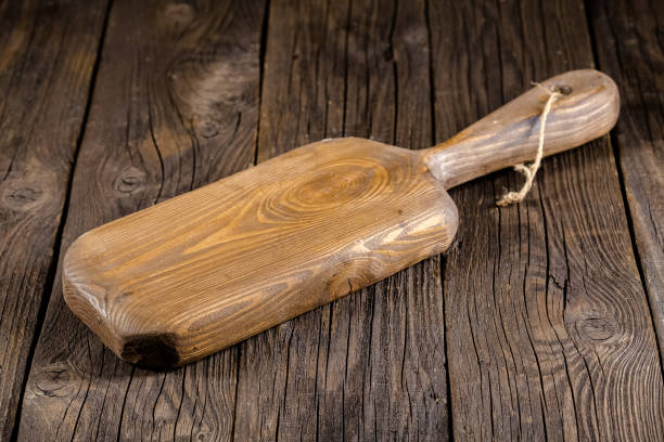 istock Russia, rustic old vintage wooden cutting board for the kitchen, with a groove structure, stripes, lies, stands on the table are cracks, black, brown, round square oval right angles sharp, rope 1148003078