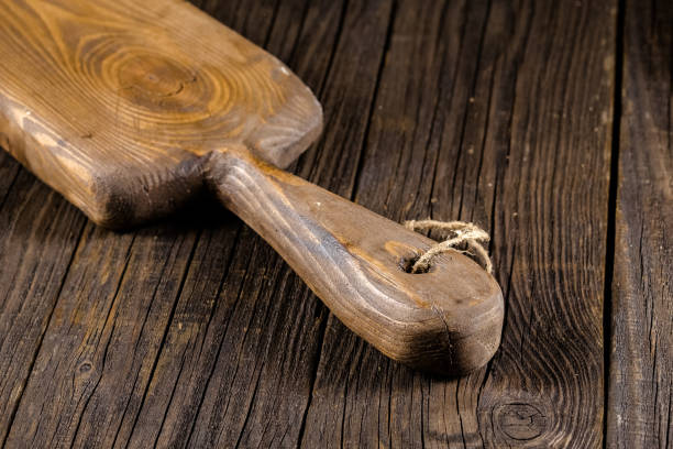 istock Russia, rustic old vintage wooden cutting board for the kitchen, with a groove structure, stripes, lies, stands on the table are cracks, black, brown, round square oval right angles sharp, rope 1148003158