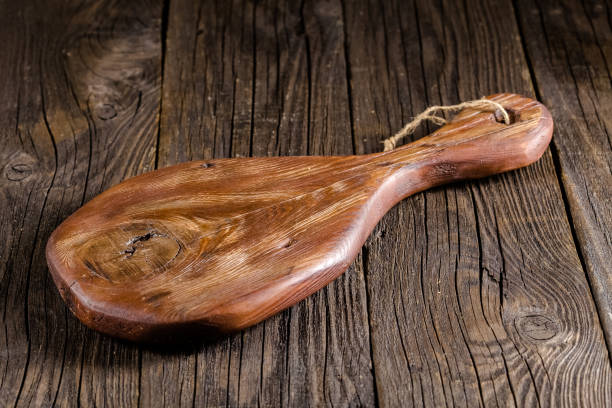istock Russia, rustic old vintage wooden cutting board for the kitchen, with a groove structure, stripes, lies, stands on the table are cracks, black, brown, round square oval right angles sharp, rope 1148003686