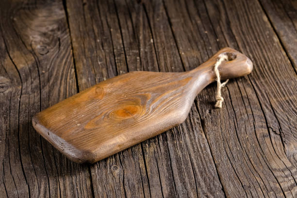 istock Russia, rustic old vintage wooden cutting board for the kitchen, with a groove structure, stripes, lies, stands on the table are cracks, black, brown, round square oval right angles sharp, rope 1148003710