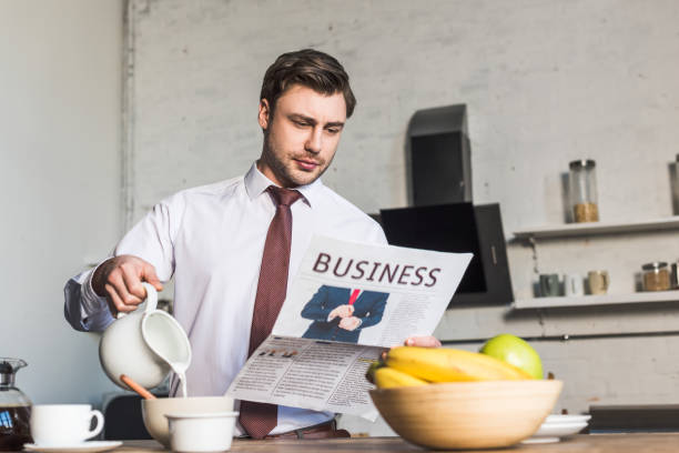 istock handsome man reading business newspaper while standing by kitchen table and pouring milk into bowl 1148004783
