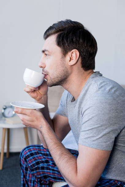 istock pensive handsome man drinking morning coffee in bedroom at home 1148004977