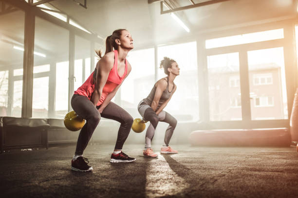 two woman lifting kettle bell in gym gym - kettle bell exercising healthy lifestyle sports clothing imagens e fotografias de stock