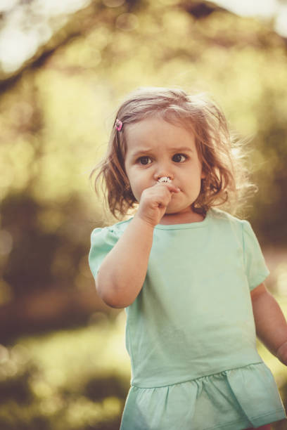 istock Little girl smelling daisy flower 1148010372