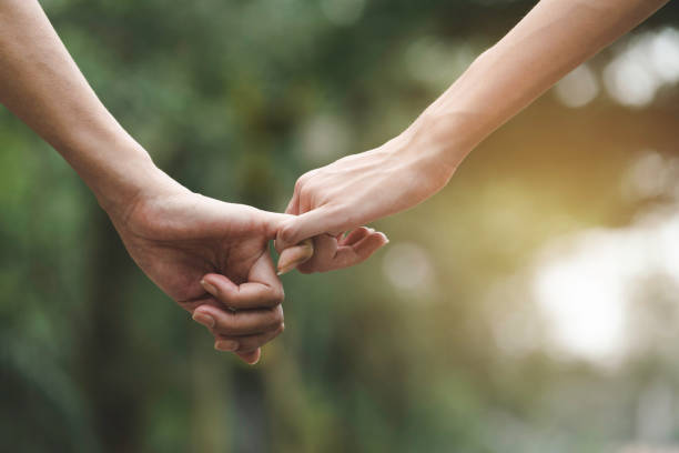 istock Closeup two person hook each other's little finger on nature background. 1148017556