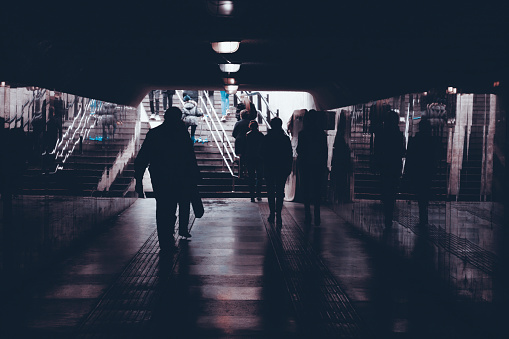 silhouettes of people in an underground pedestrian crossing