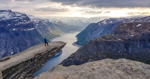 istock Norway - Young man standing at the edge of Trolltunga 1148019487